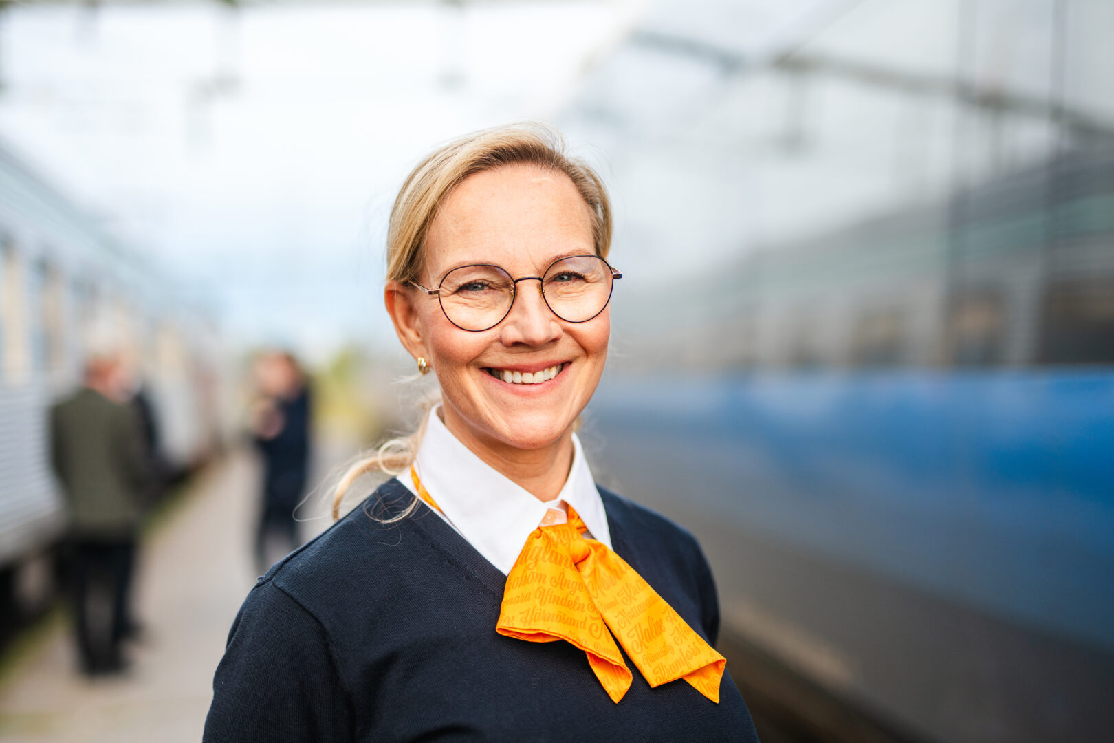 Tågvärd med Norrtågsuniform på perrong med ett Norrtåg i bakgrunden