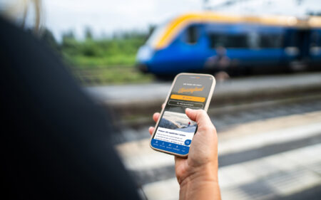 Mobiltelefon med Norrtågs hemsida som bakgrund. Bortanför syns ett Norrtågs-fordon.